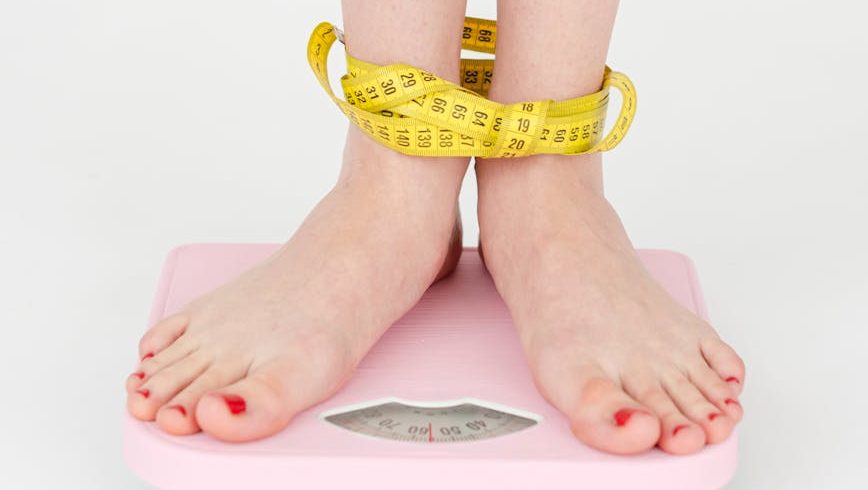 woman tied with measuring tape standing on scales