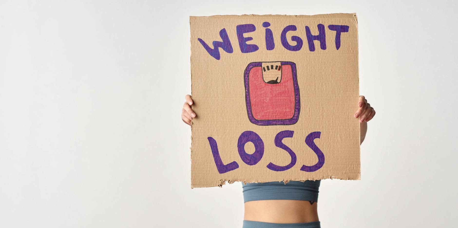 person holding a cardboard with weight loss message